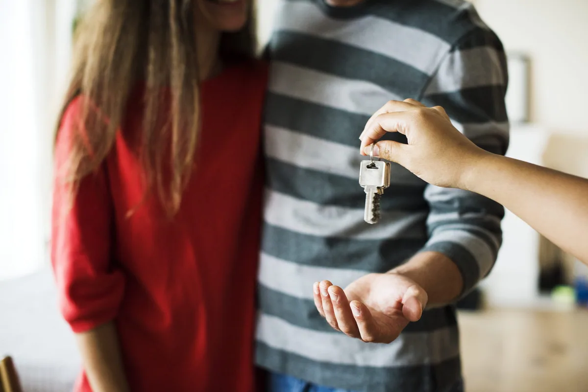 Pareja recibiendo las llaves de una vivienda, imagen editorial de Grupo Suárez.